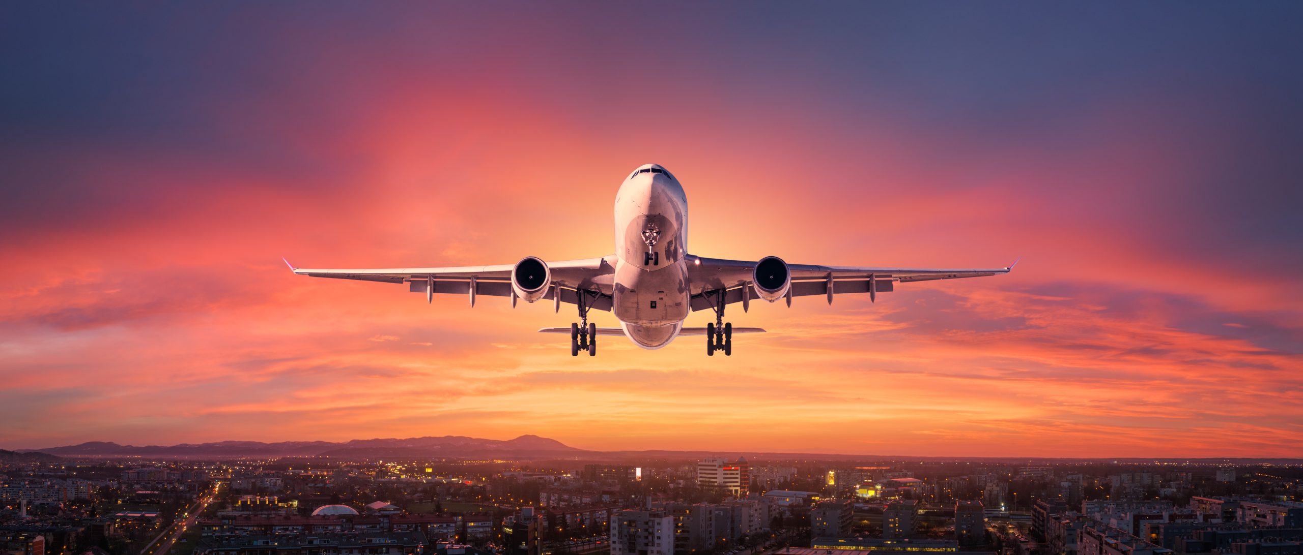 Airplane is flying in colorful sky over the city at night